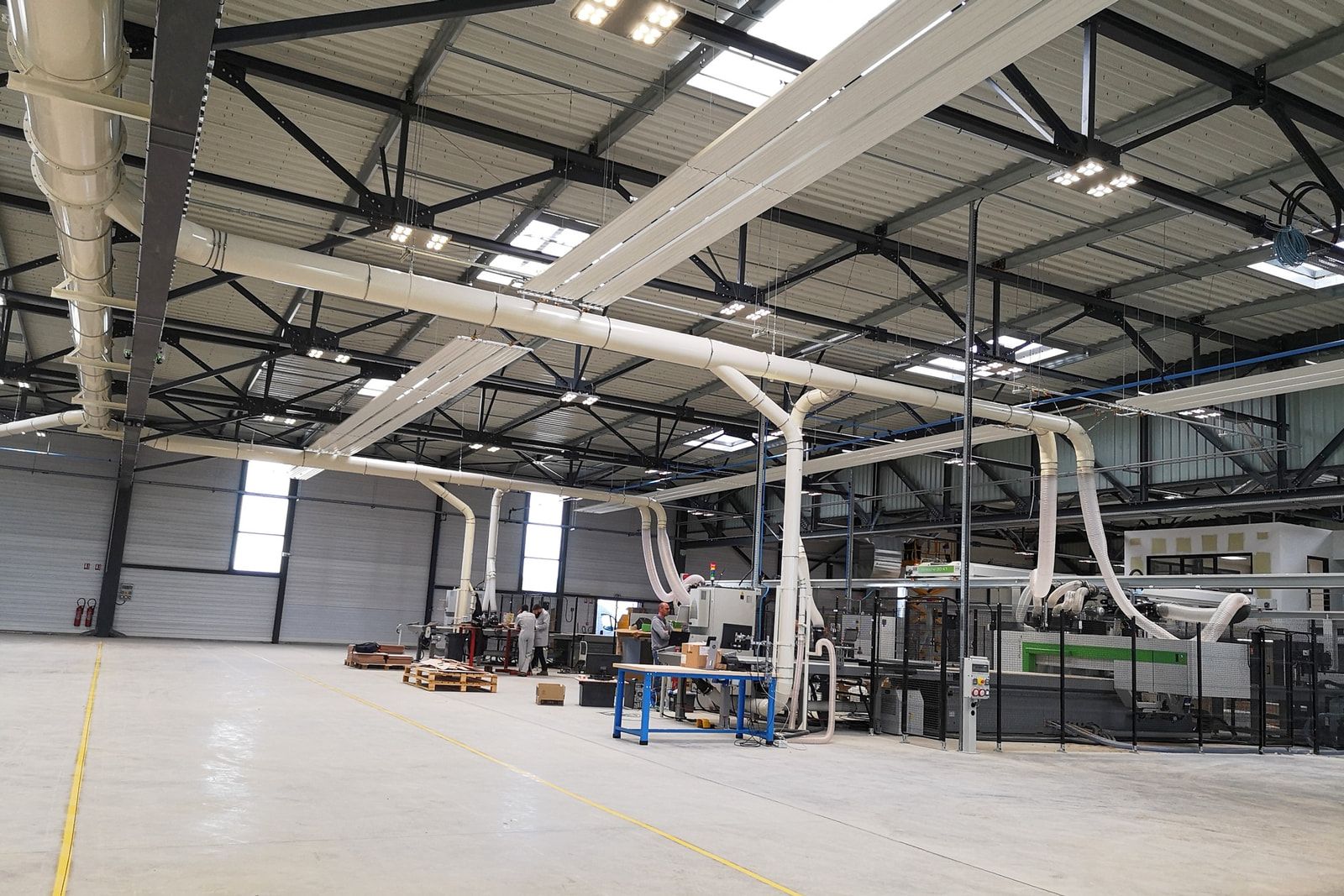 Atelier de découpe et d’usinage numériques de Fountaine Pajot au Thou : réseaux d’aspiration des machines suspendus sous la charpente.