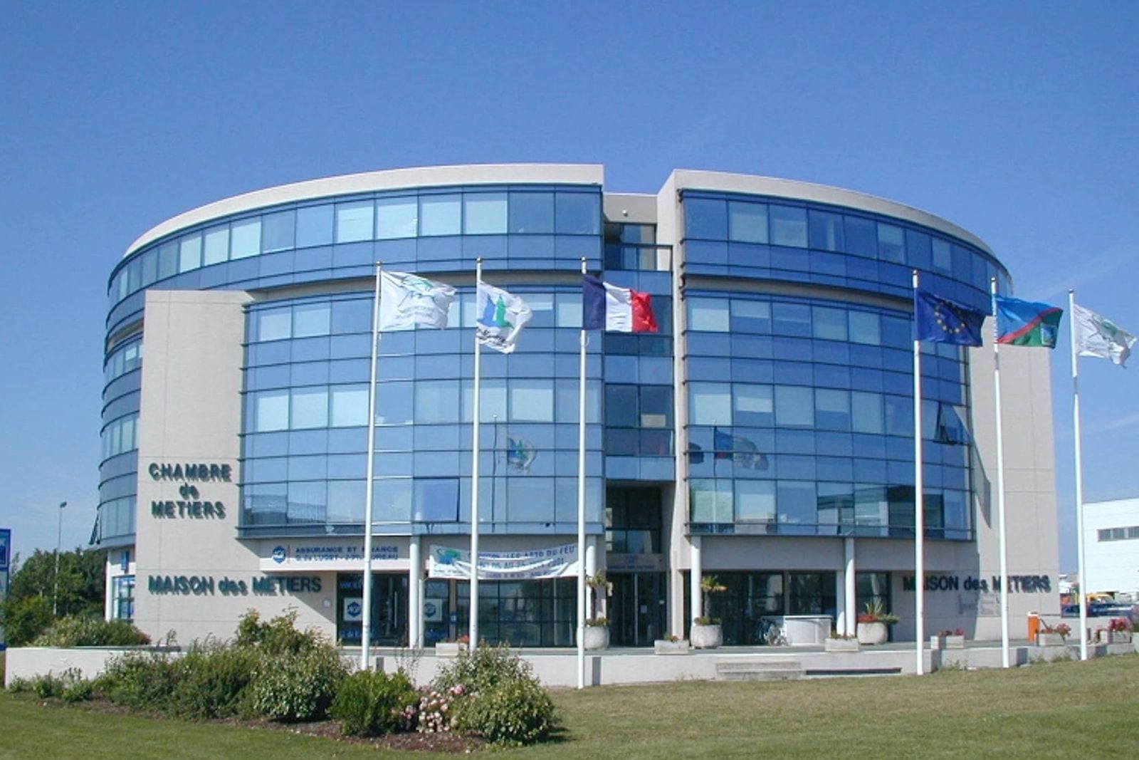 Maison des Métiers de la Chambre des Métiers et de l’Artisanat à La Rochelle : bâtiment circulaire très vitré, mâts à drapeaux.