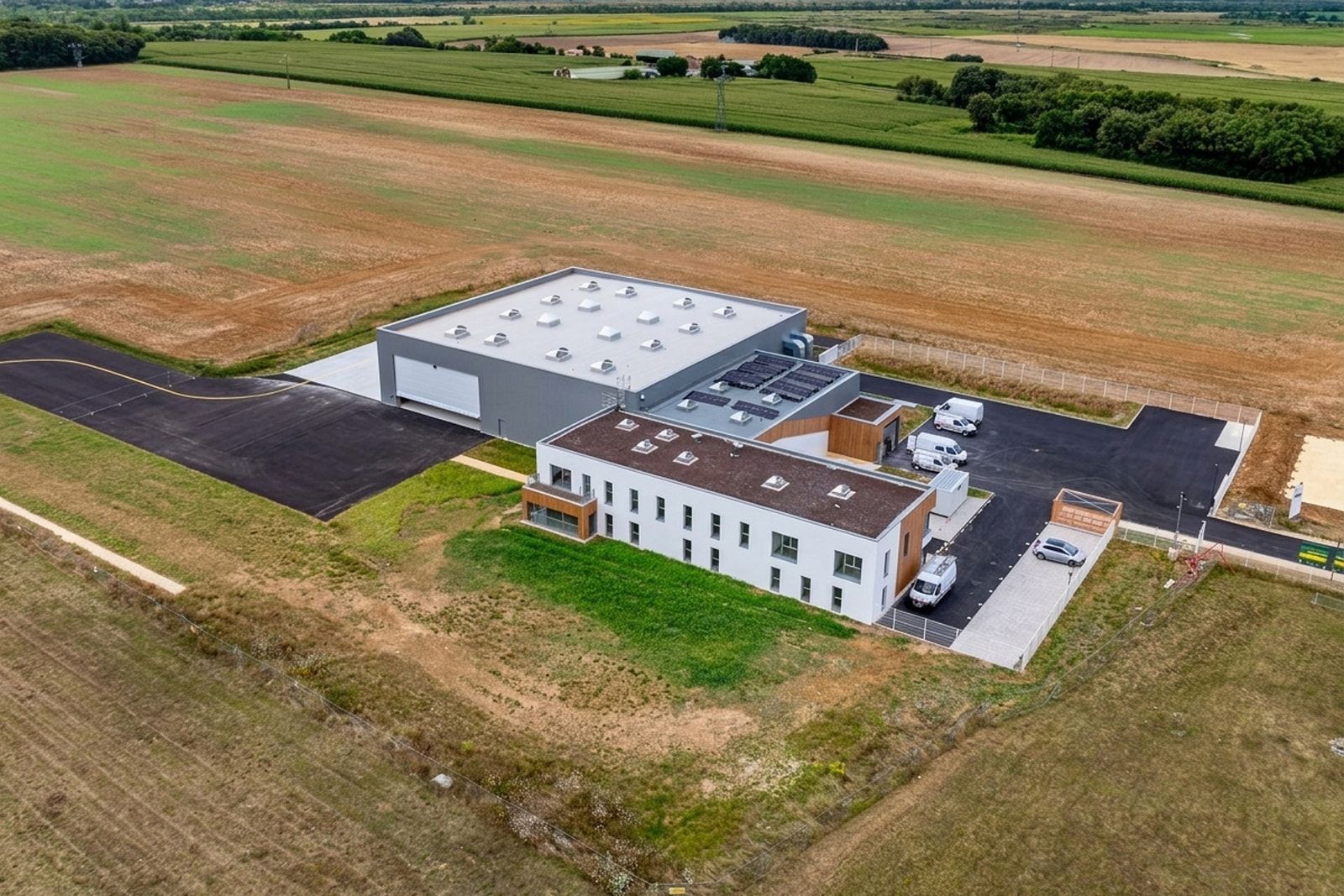 Vue aérienne du bâtiment VoltAero, aéroport de Rochefort – Saint-Agnant : hall d’assemblage d’avions, aile de bureaux et panneaux photovoltaïques.