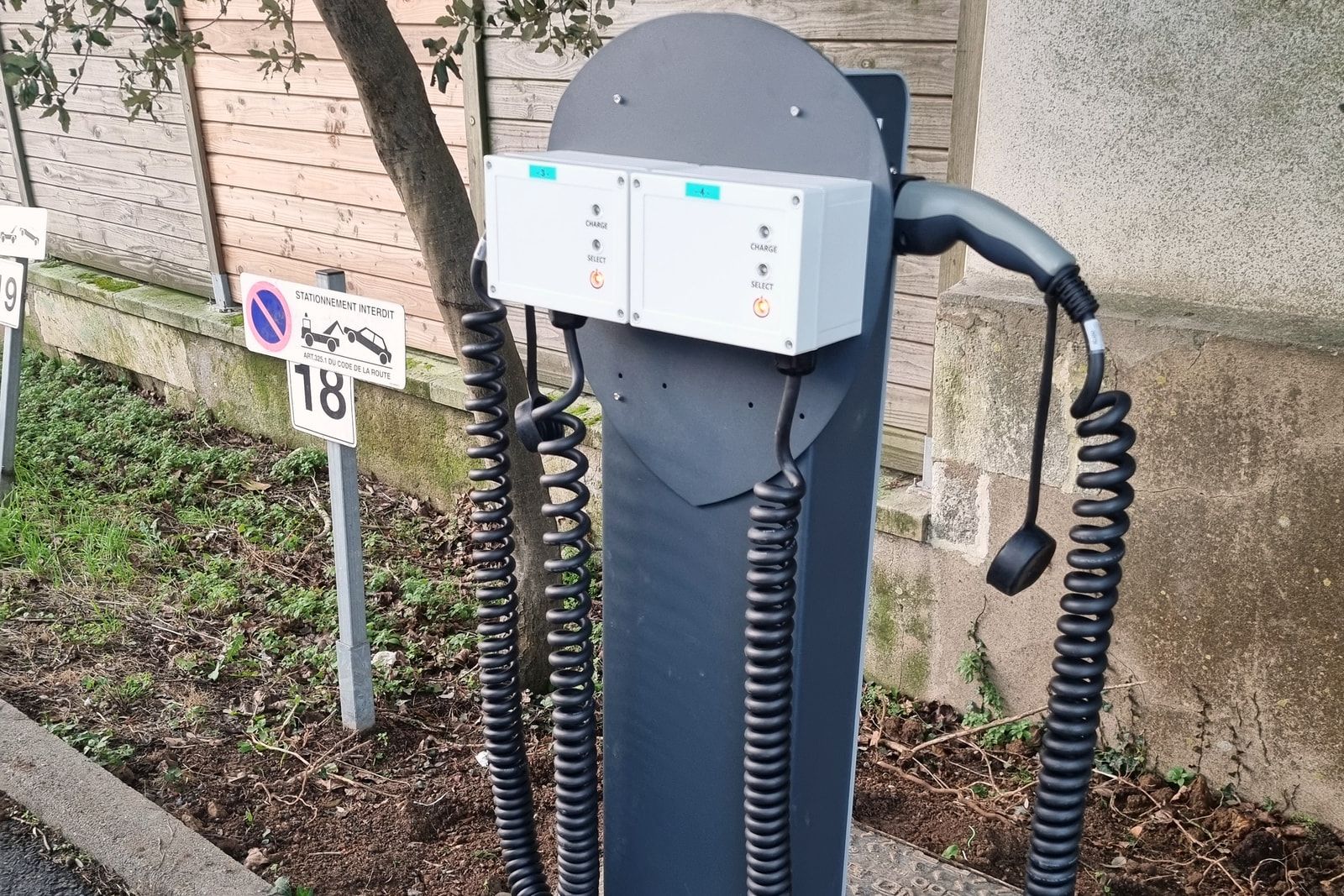 Borne de recharge double des véhicules de service de la CPAM à La Rochelle, cordons lovés, en limite de parcelle.