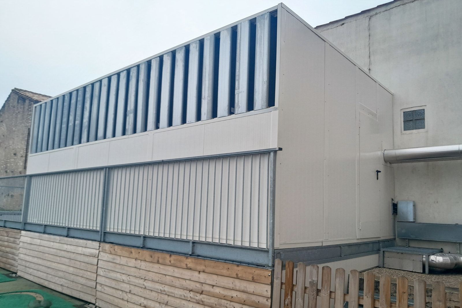 Écran acoustique à lames autour des pompes à chaleur de l’école maternelle de La Flotte-en-Ré, en limite de cour.