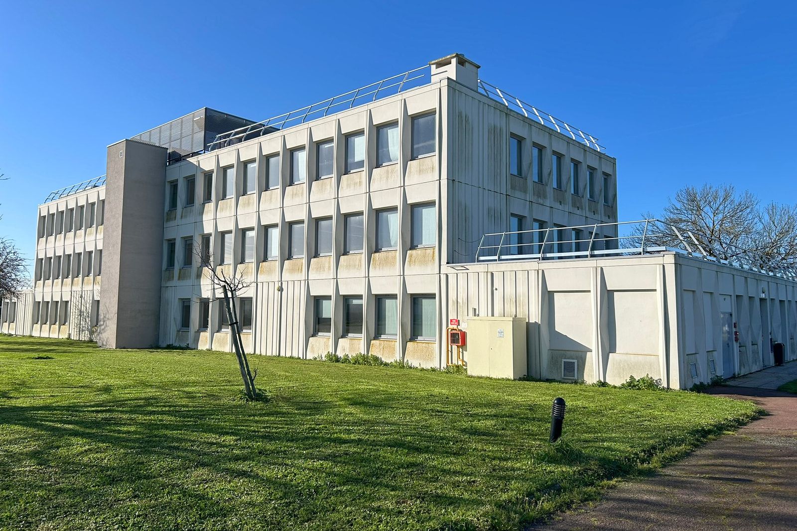Façade du bâtiment d’enseignement de l’École nationale des douanes, rue du Jura à La Rochelle, bordé d’une pelouse.