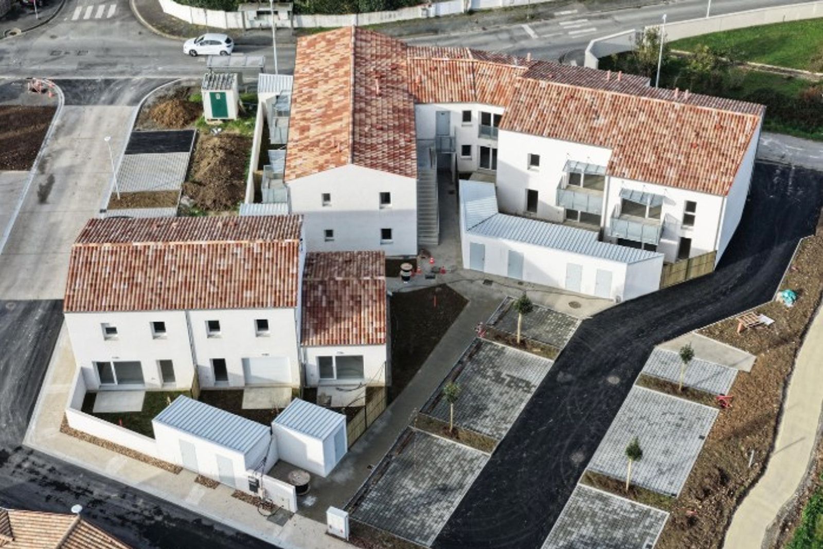 Vue aérienne de Maubec à Chagnolet, Dompierre-sur-Mer : treize logements sociaux en trois bâtiments enduits blancs sous tuiles.