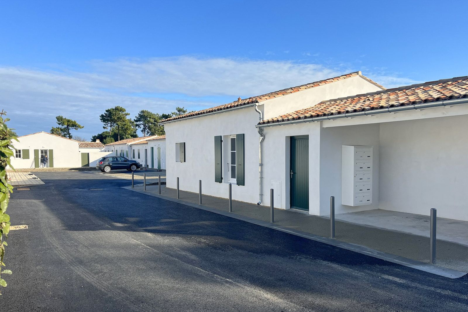Maisons accolées de plain-pied du Pas des Bœufs au Bois-Plage-en-Ré : enduit blanc, tuiles canal et volets verts.