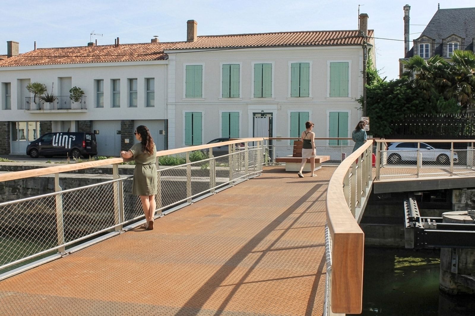 Passerelle cyclo-piétonne du Carreau d’Or à Marans : platelage acier, garde-corps en câbles et main courante bois qui loge l’éclairage à leds.