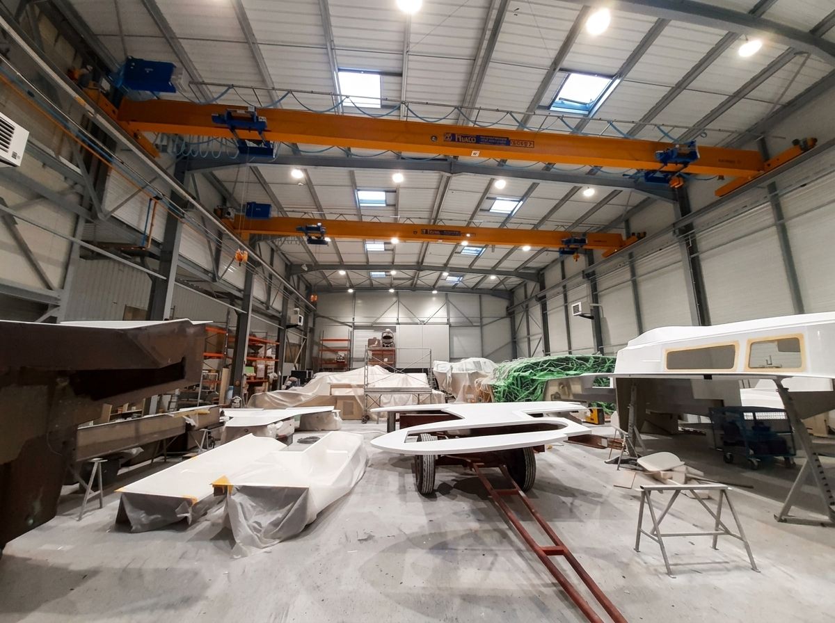 Nef du chantier naval Pinta Techni Yachts sous deux ponts roulants, pièces de coque en préparation au sol.