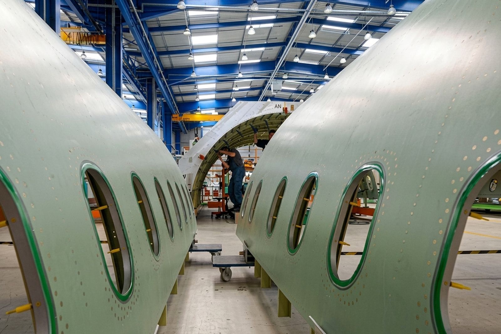 Tronçons de fuselage percés de hublots dans un hall d’assemblage aéronautique du site Airbus de Rochefort.