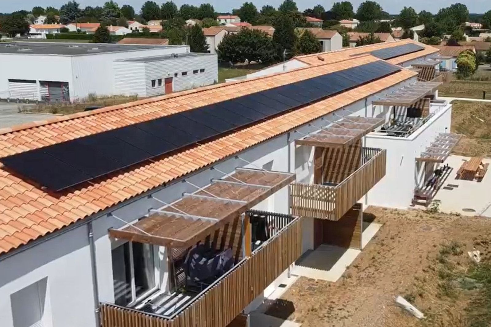 Résidence intergénérationnelle de Saint-Agnant : toiture de tuiles portant ses panneaux photovoltaïques, balcons bois sous pergolas.
