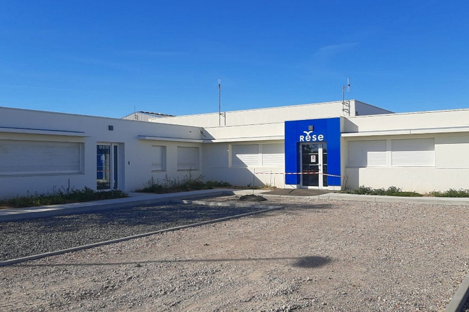Siège de la RESE à Aigrefeuille-d’Aunis : bureaux enduits blancs et entrée signalée par un volume bleu à l’enseigne de la régie.